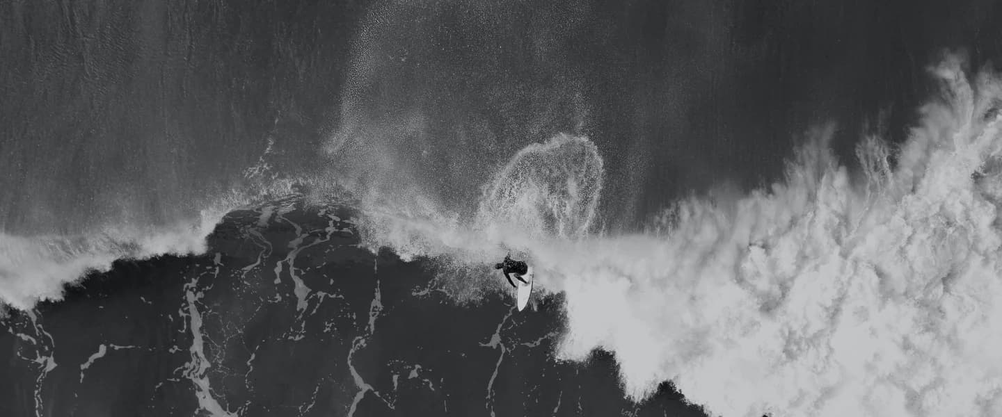 Aerial view of a surfer riding a huge breaking wave