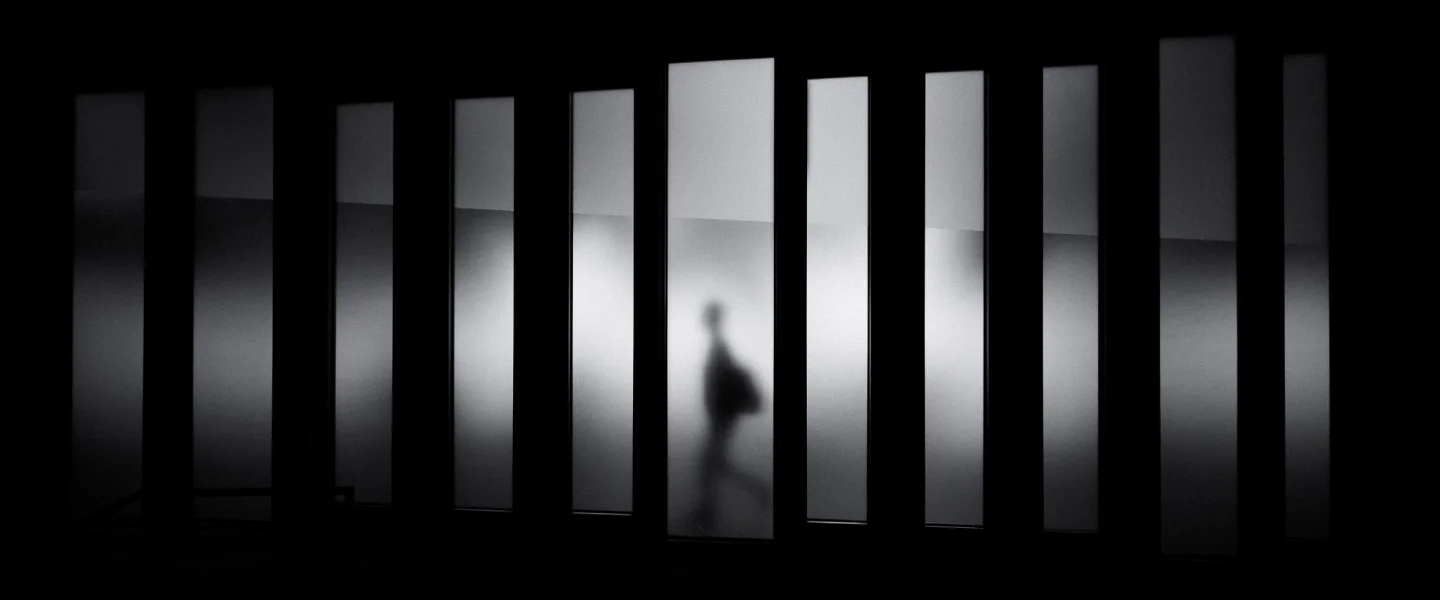 Silhouette of a person walking behind frosted glass panels